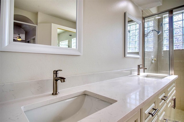 bathroom featuring vanity, ceiling fan, a textured ceiling, and tiled shower