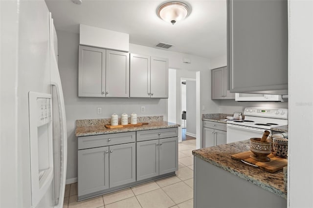 kitchen featuring white appliances, gray cabinetry, light tile patterned floors, and stone countertops