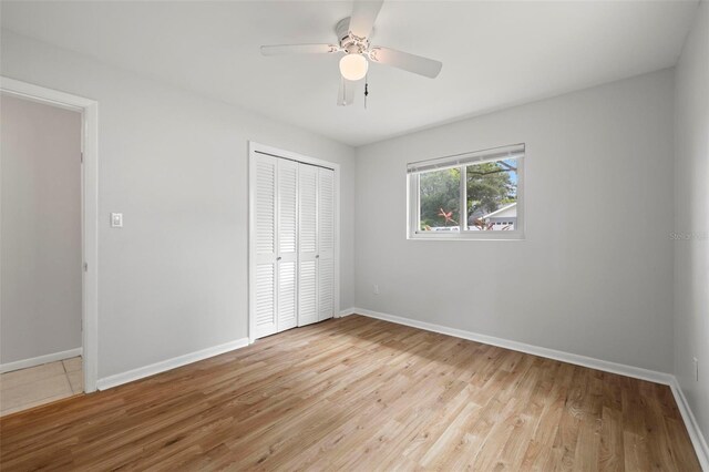 unfurnished bedroom featuring ceiling fan, a closet, and light wood-type flooring