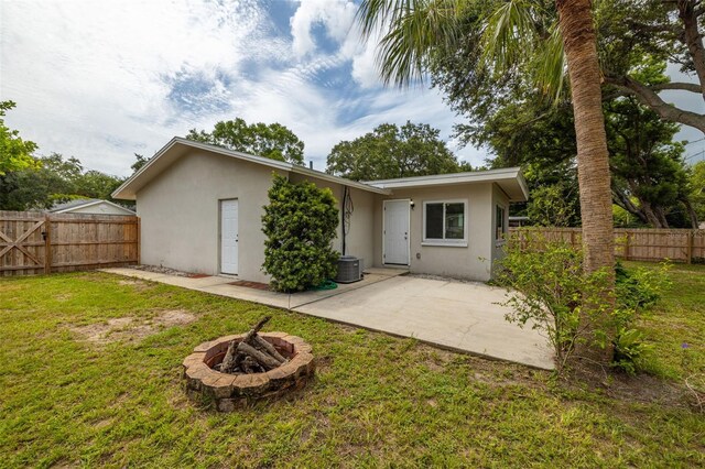 back of property featuring a lawn, a patio, and a fire pit