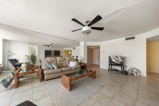 living room with ceiling fan, light tile patterned flooring, and a textured ceiling