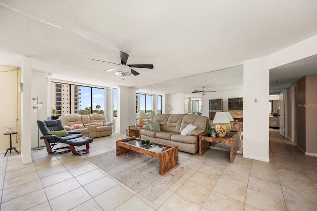 tiled living room with ceiling fan, a wall of windows, and a textured ceiling