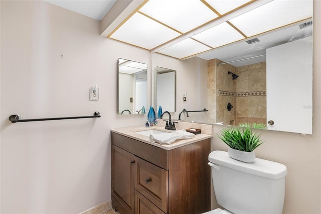 bathroom with tiled shower, vanity, and toilet