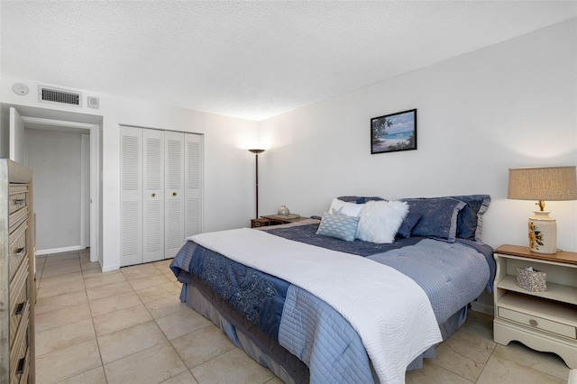 bedroom with a textured ceiling, light tile patterned floors, and a closet