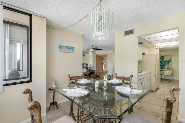 dining room with light tile patterned floors, ceiling fan with notable chandelier, and a textured ceiling