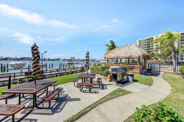 view of community featuring a water view, a dock, and a patio