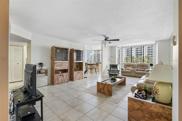 living room with a textured ceiling, ceiling fan, light tile patterned floors, and floor to ceiling windows