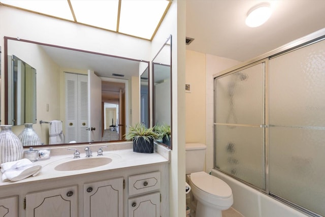 full bathroom with bath / shower combo with glass door, toilet, and vanity