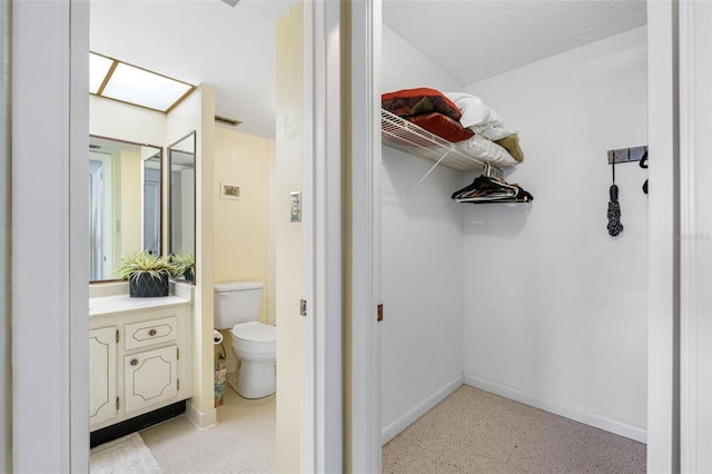 bathroom featuring toilet, a textured ceiling, and vanity