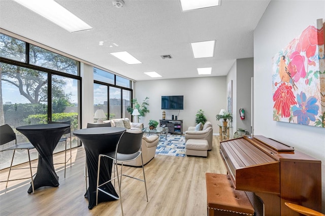 living room featuring a textured ceiling, expansive windows, and light wood-type flooring