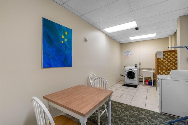 dining room featuring washing machine and dryer, a paneled ceiling, and light tile patterned floors