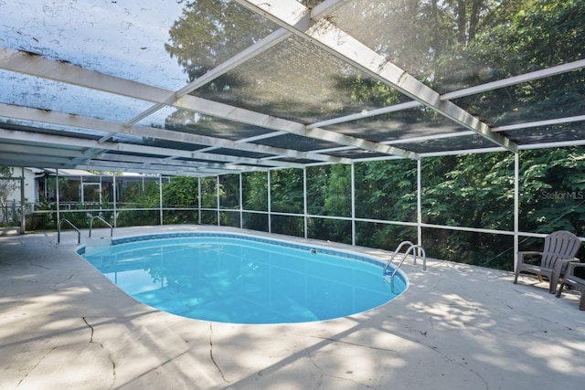 view of pool with glass enclosure and a patio