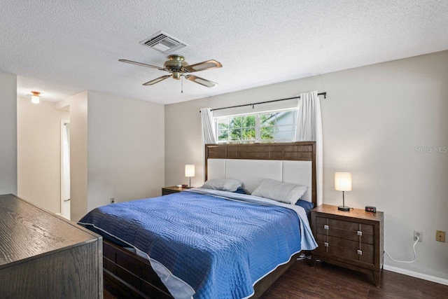 bedroom with ceiling fan, dark wood-type flooring, and a textured ceiling