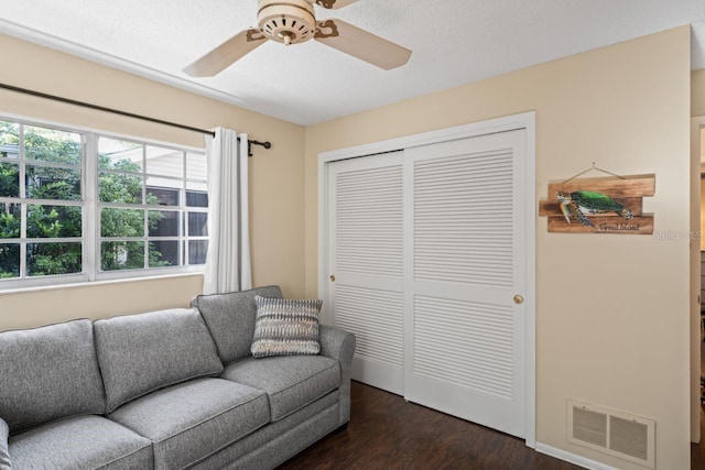 living room with ceiling fan and dark wood-type flooring