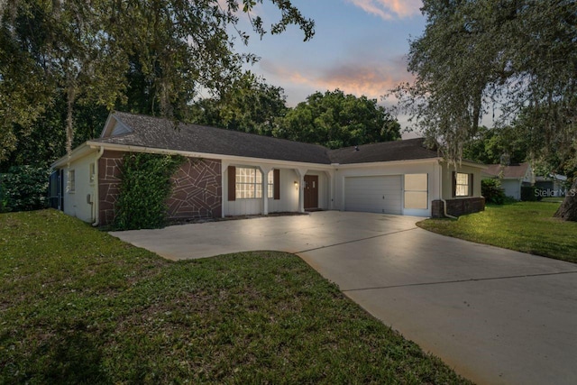 single story home featuring a garage and a yard