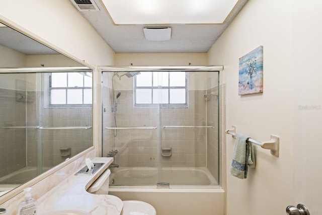 bathroom with toilet, combined bath / shower with glass door, and a healthy amount of sunlight