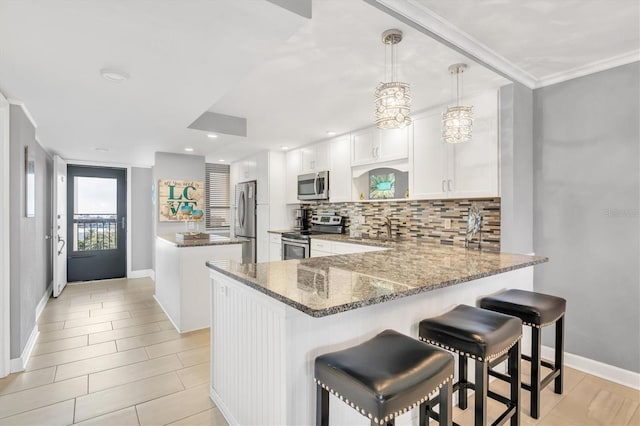 kitchen featuring sink, white cabinetry, appliances with stainless steel finishes, kitchen peninsula, and stone counters