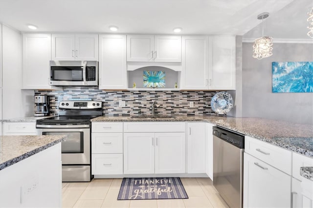 kitchen with appliances with stainless steel finishes, decorative light fixtures, sink, white cabinets, and light stone counters