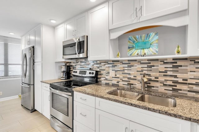 kitchen with white cabinetry, appliances with stainless steel finishes, sink, and stone countertops