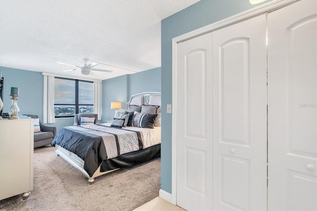 carpeted bedroom featuring ceiling fan and a textured ceiling