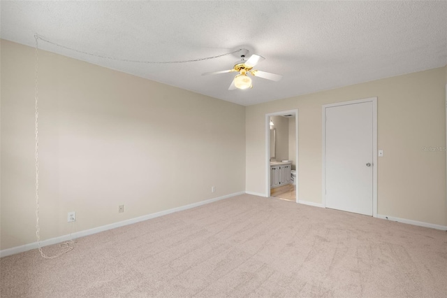 unfurnished bedroom featuring a textured ceiling, carpet flooring, ceiling fan, and ensuite bath