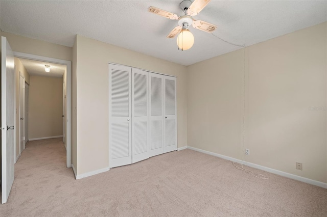 unfurnished bedroom with a closet, ceiling fan, light colored carpet, and a textured ceiling