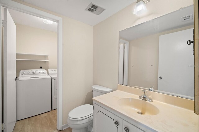 bathroom with vanity, toilet, wood-type flooring, and washer and clothes dryer