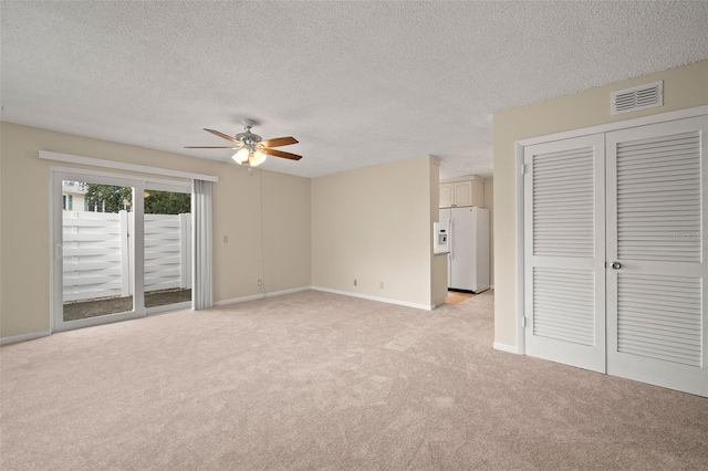 unfurnished bedroom with a textured ceiling, access to exterior, ceiling fan, and white refrigerator with ice dispenser