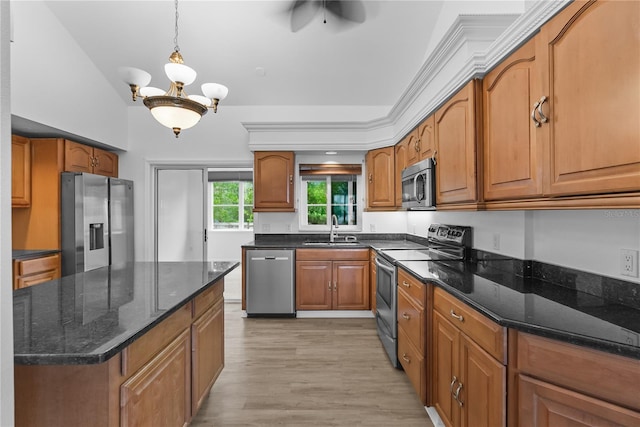 kitchen with sink, stainless steel appliances, light hardwood / wood-style floors, decorative light fixtures, and dark stone counters