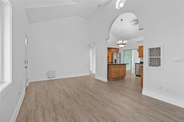 unfurnished living room featuring high vaulted ceiling, a notable chandelier, and light wood-type flooring