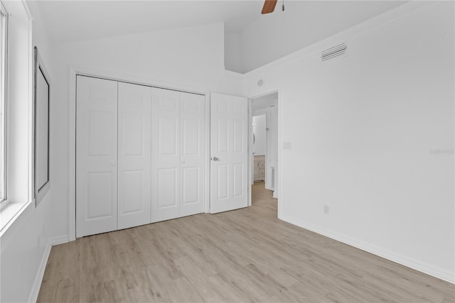 unfurnished bedroom with vaulted ceiling, light hardwood / wood-style floors, a closet, and ceiling fan