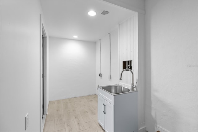 kitchen featuring sink, light hardwood / wood-style flooring, and white cabinets