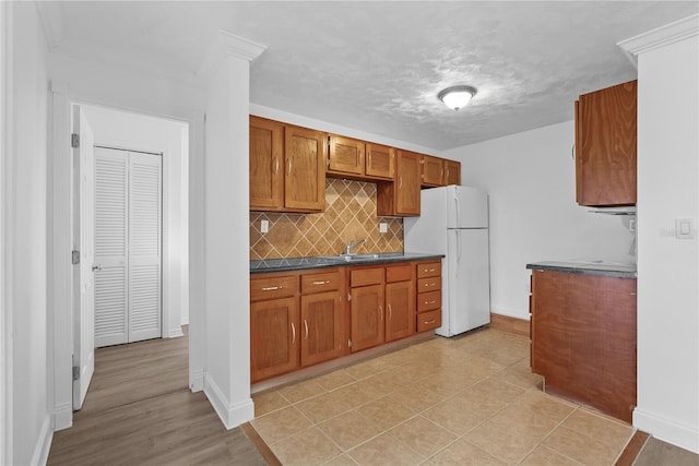 kitchen featuring white refrigerator, sink, a textured ceiling, and decorative backsplash