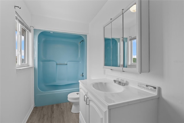 full bathroom featuring toilet,  shower combination, wood-type flooring, plenty of natural light, and vanity