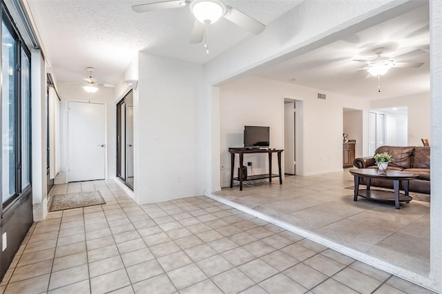 interior space featuring a textured ceiling, light tile patterned floors, and ceiling fan