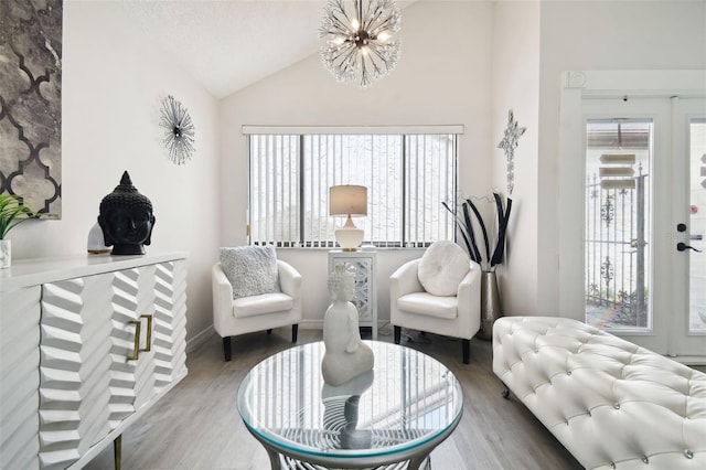 living room with a notable chandelier, a textured ceiling, hardwood / wood-style floors, and vaulted ceiling