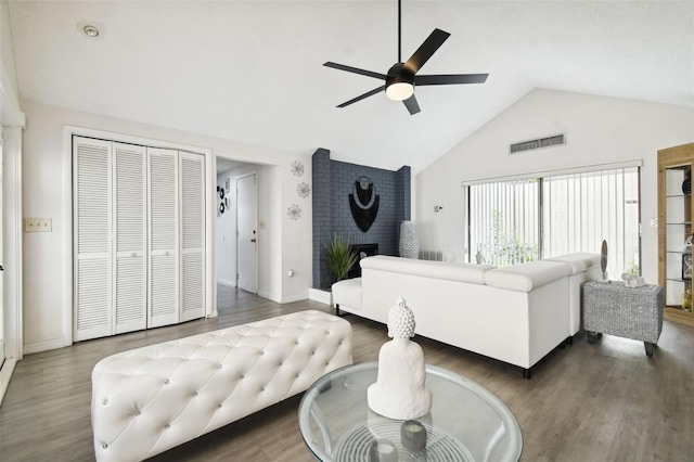 living room with a brick fireplace, high vaulted ceiling, wood-type flooring, ceiling fan, and brick wall