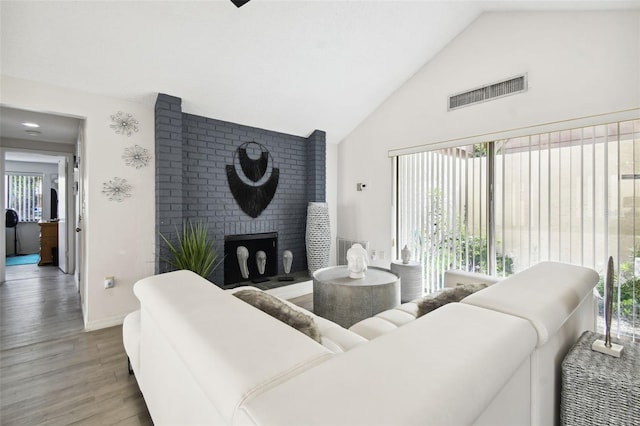 living room with vaulted ceiling, a fireplace, hardwood / wood-style flooring, and a healthy amount of sunlight