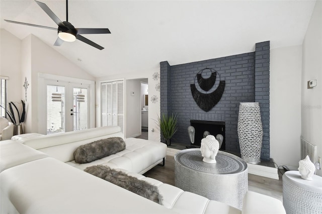 living room featuring ceiling fan, french doors, high vaulted ceiling, a fireplace, and wood-type flooring