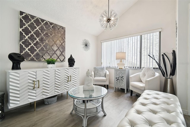 living room featuring a notable chandelier, a textured ceiling, vaulted ceiling, and hardwood / wood-style flooring