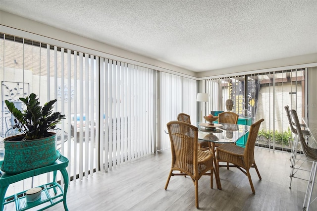 dining space featuring light hardwood / wood-style flooring and a textured ceiling