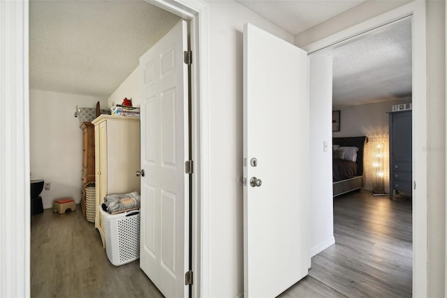 hallway with light hardwood / wood-style flooring and a textured ceiling