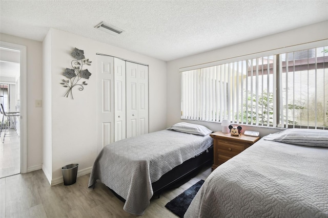 bedroom with hardwood / wood-style flooring, a textured ceiling, and a closet