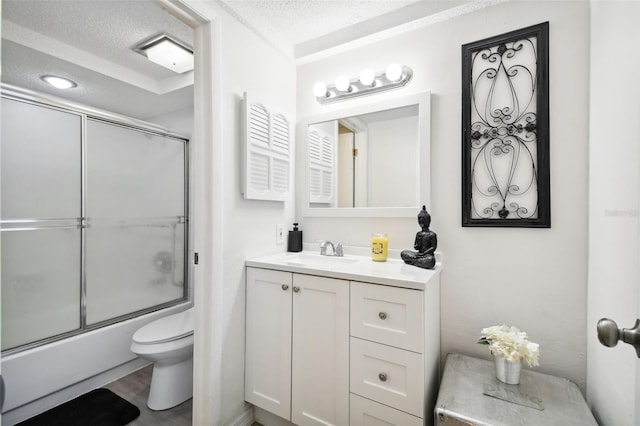 full bathroom with bath / shower combo with glass door, vanity, a textured ceiling, and toilet