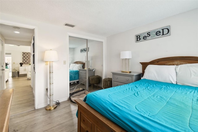 bedroom with a closet, a textured ceiling, and light wood-type flooring