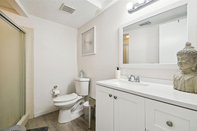 bathroom featuring toilet, a shower with shower door, wood-type flooring, a textured ceiling, and vanity