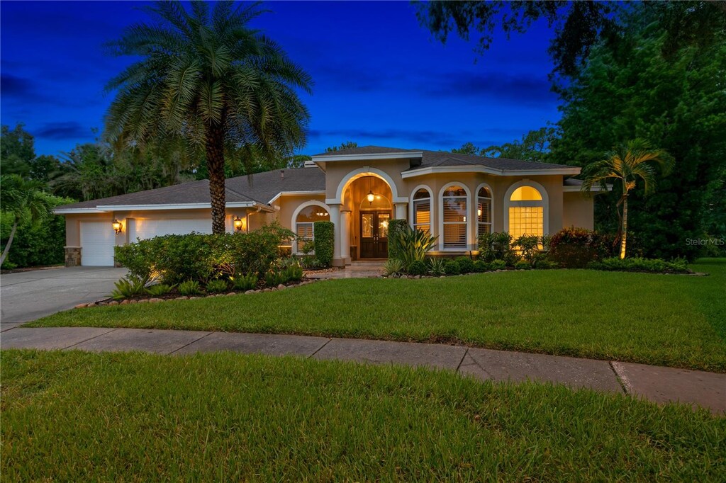 mediterranean / spanish house with a garage and a lawn