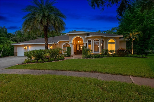 mediterranean / spanish house with a garage and a lawn