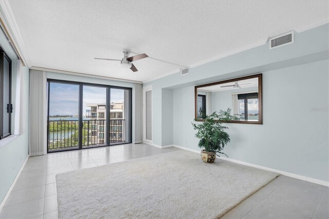 tiled empty room featuring ornamental molding, a textured ceiling, and ceiling fan