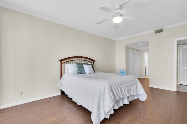 bedroom with a closet, hardwood / wood-style flooring, crown molding, a textured ceiling, and ceiling fan